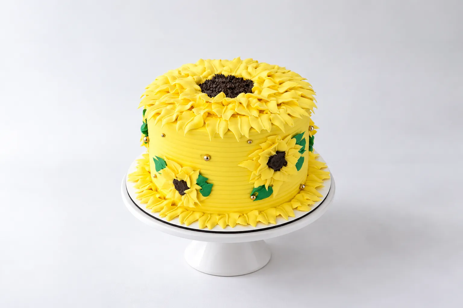 Torta amarilla con grandes flores, centros oscuros y hojas verdes