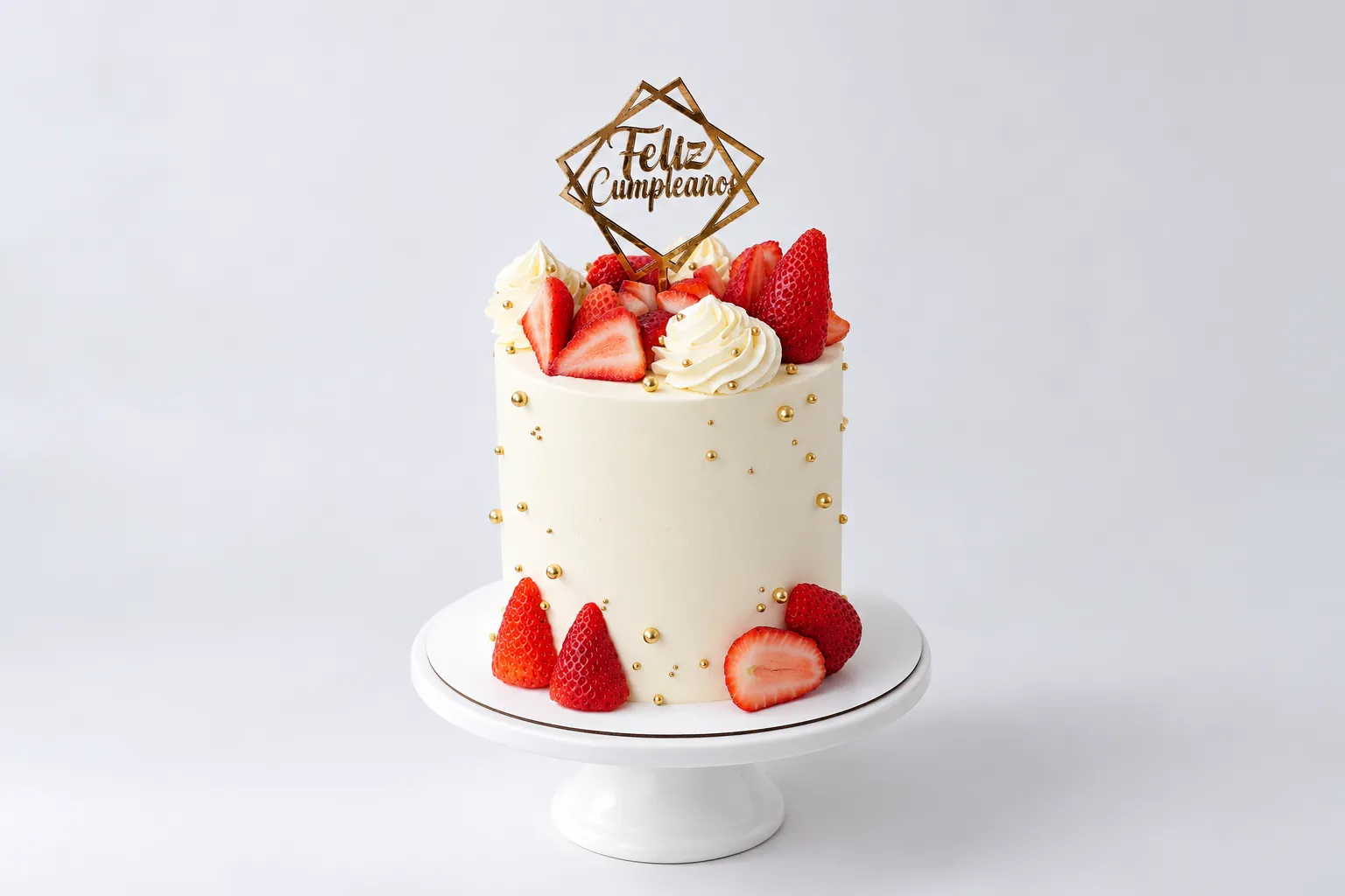 Torta blanca alta con frutas rojas en la base y adorno geométrico dorado