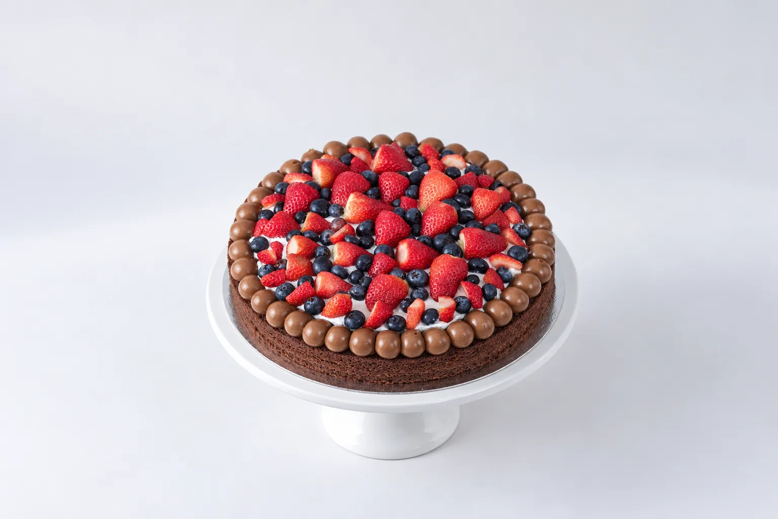 Torta baja oscura con una corona de bolitas y frutas rojas y azules